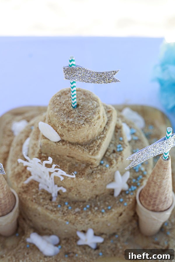 A sandcastle cake adorned with delicate white chocolate seashells and other coastal-themed decorations.