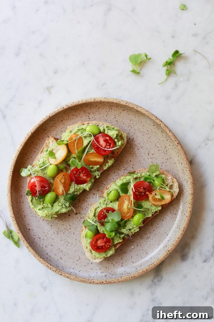 Edamame hummus on toast with cherry tomatoes and microgreens. A perfect healthy and protein-rich breakfast or lunch idea.
