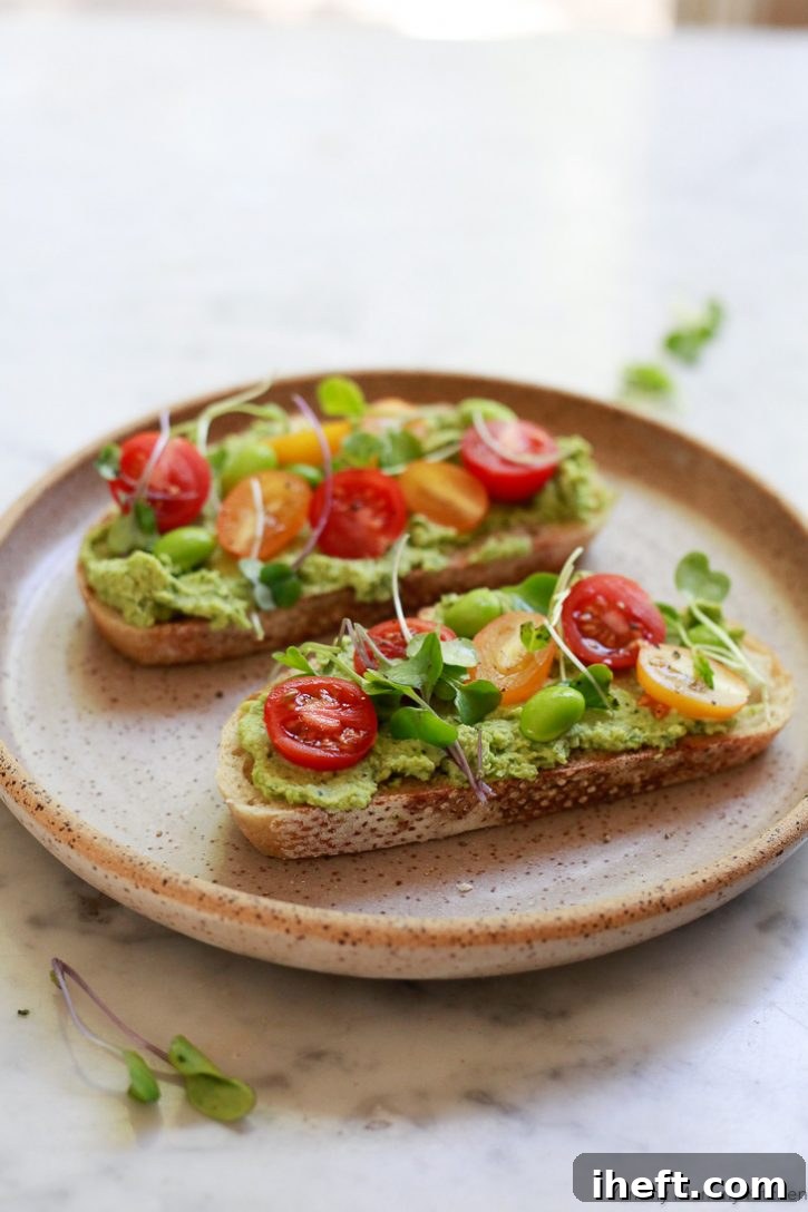 This healthy vegan edamame basil hummus recipe is perfect on sourdough toast with cherry tomatoes and microgreens for a plant based lunch or snack.