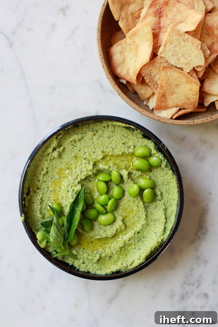 A bowl of homemade vegan edamame basil hummus is the perfect healthy party dip served with crudite veggies or pita chips. Delicious and vibrant green.