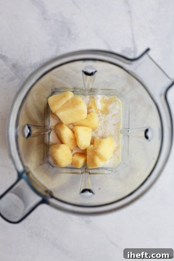 Ingredients for healthier virgin pina coladas in a Vitamix blender include frozen pineapple chunks, pineapple juice, and coconut cream. 