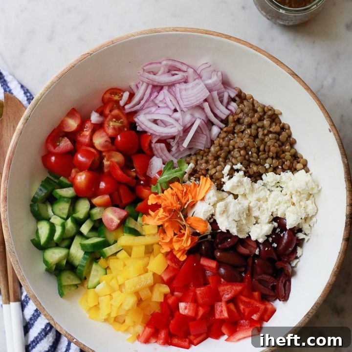 A beautiful healthy Mediterranean lentil salad with tomatoes, cucumber, olives, feta, bell pepper, and green lentils.