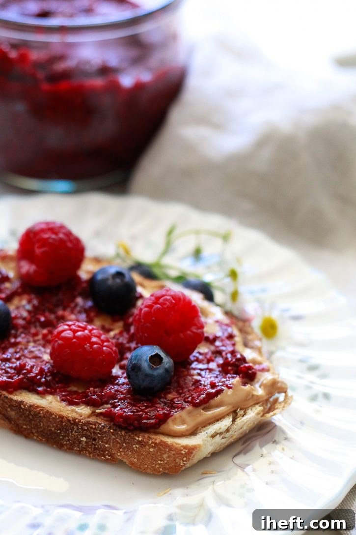 Vibrant blueberry and raspberry chia jam spread generously on toast with a layer of peanut butter. This healthy homemade chia jam is effortlessly made with fresh or frozen berries and contains no added sugar, perfect for a nutritious breakfast.