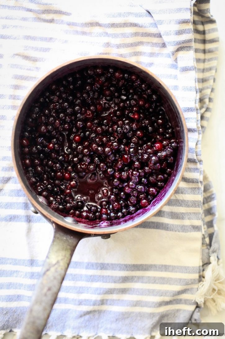 Fresh blueberries simmering in a gleaming copper saucepan, ready to be transformed into healthy blueberry chia jam. The steam gently rises from the fruit.