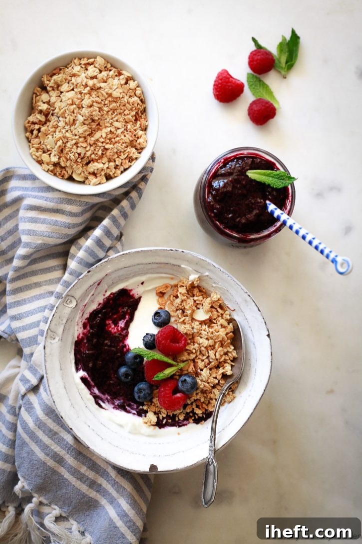 A vibrant vegan breakfast bowl topped with creamy coconut yogurt, crunchy granola, fresh berries, and a generous dollop of blueberry chia jam. A perfect example of how to use this easy and healthy chia jam recipe.