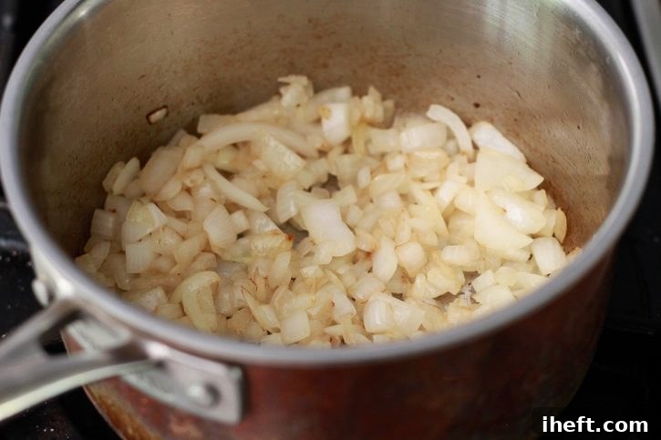 Diced yellow onions gently sautéing in a saucepan, infusing the oil with their sweet aroma as they become tender.