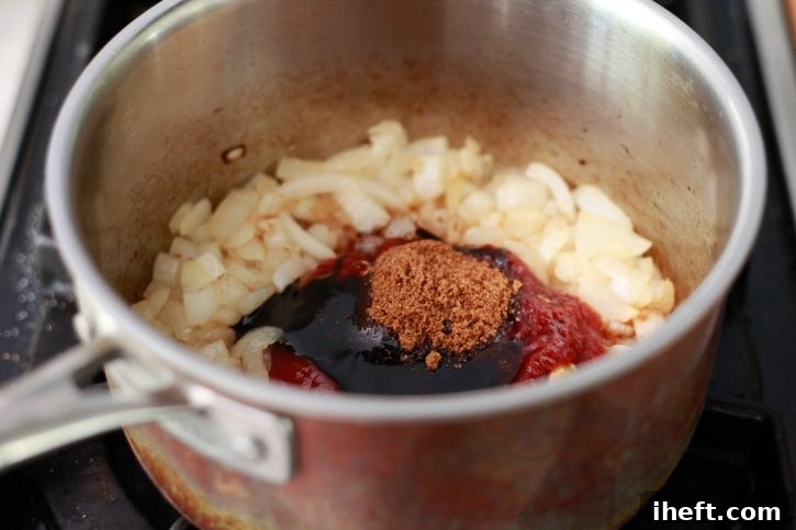 The savory and sweet ingredients for the baked beans sauce are carefully added to the softened onions in the saucepan, ready to be combined.