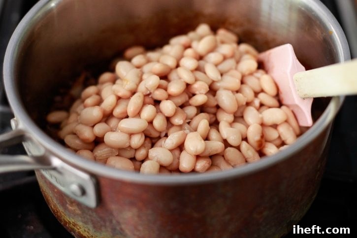 Tender white beans are carefully folded into the savory-sweet onion and sauce mixture, beginning their transformation into homemade vegetarian baked beans.