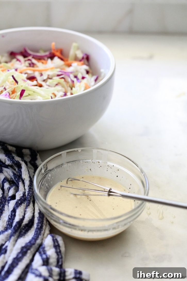 A small glass bowl containing freshly whisked vegan coleslaw dressing, perfectly creamy and ready to be poured over a bowl of crisp shredded slaw.