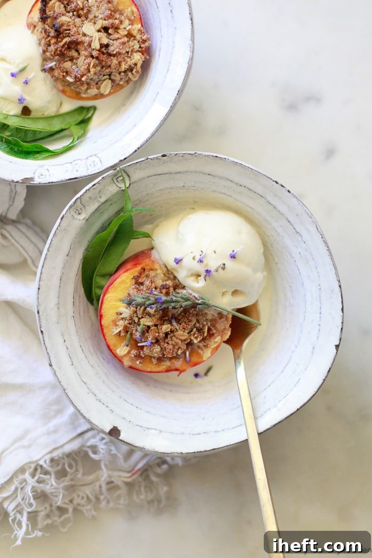 Beautiful miniature peach crisps. Baked peaches topped with a gluten-free vegan oatmeal crumble topping and served with vanilla ice cream. These baked peaches are topped with fresh lavender flowers. 