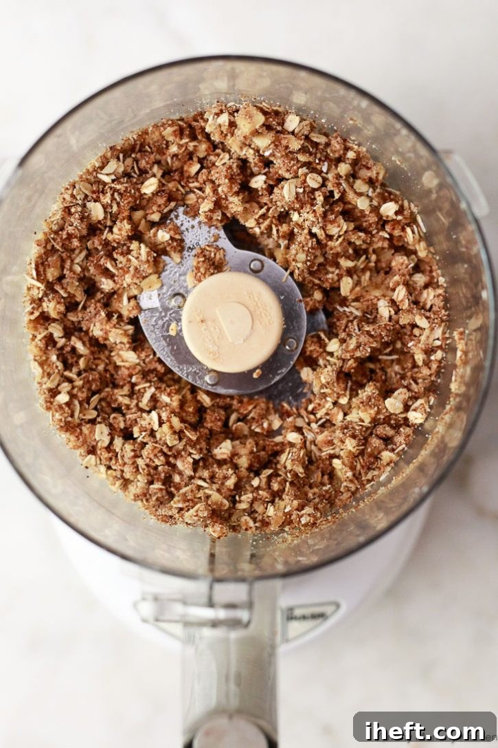 Oatmeal fruit crisp topping in a food processor is ready to top peaches. 