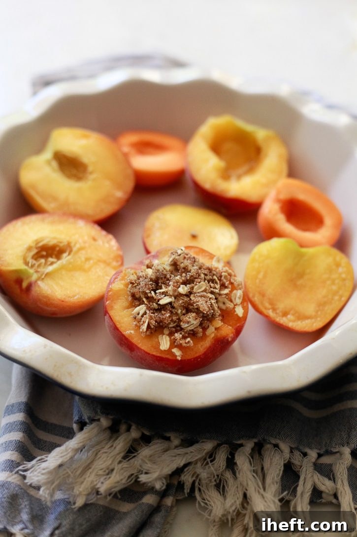 Fresh peaches in a baking dish get topped with a fruit crisp topping of nuts and oats. 