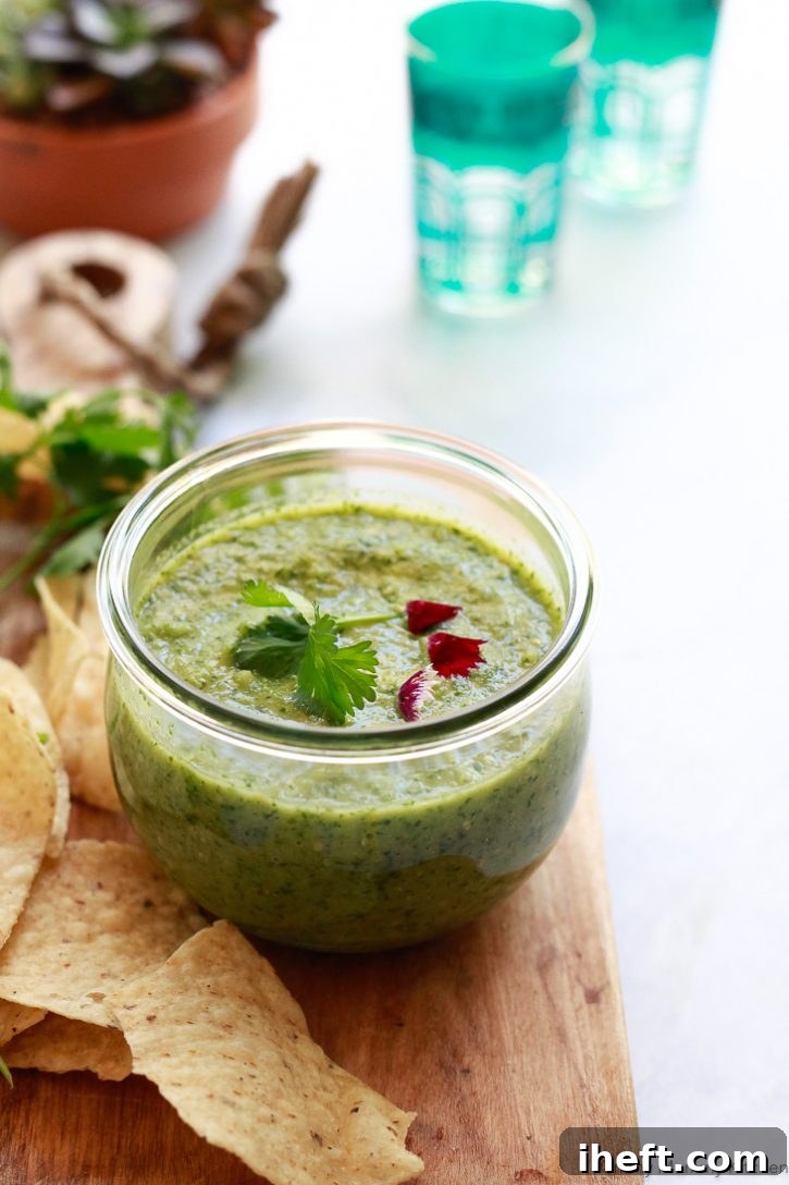 A jar of homemade green salsa verde with freshly roasted tomatillos served with chips. 