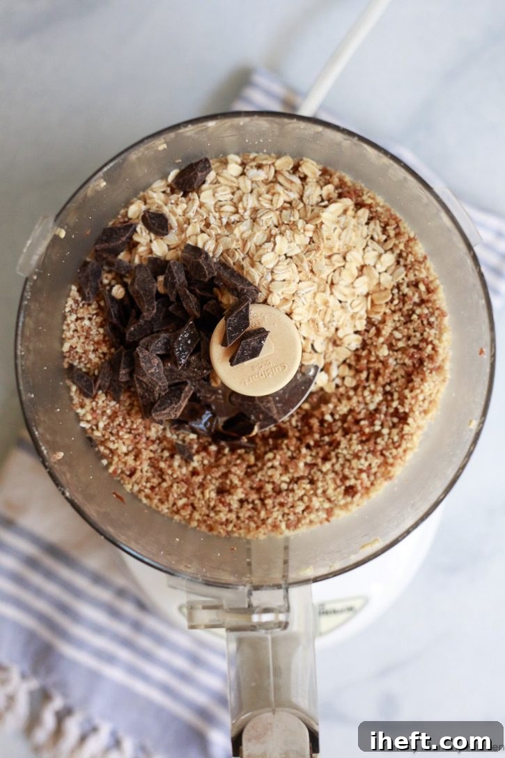 Wholesome oats and luscious dark chocolate being carefully added to a food processor, soon to be transformed into healthy no-bake oatmeal cookie bites.