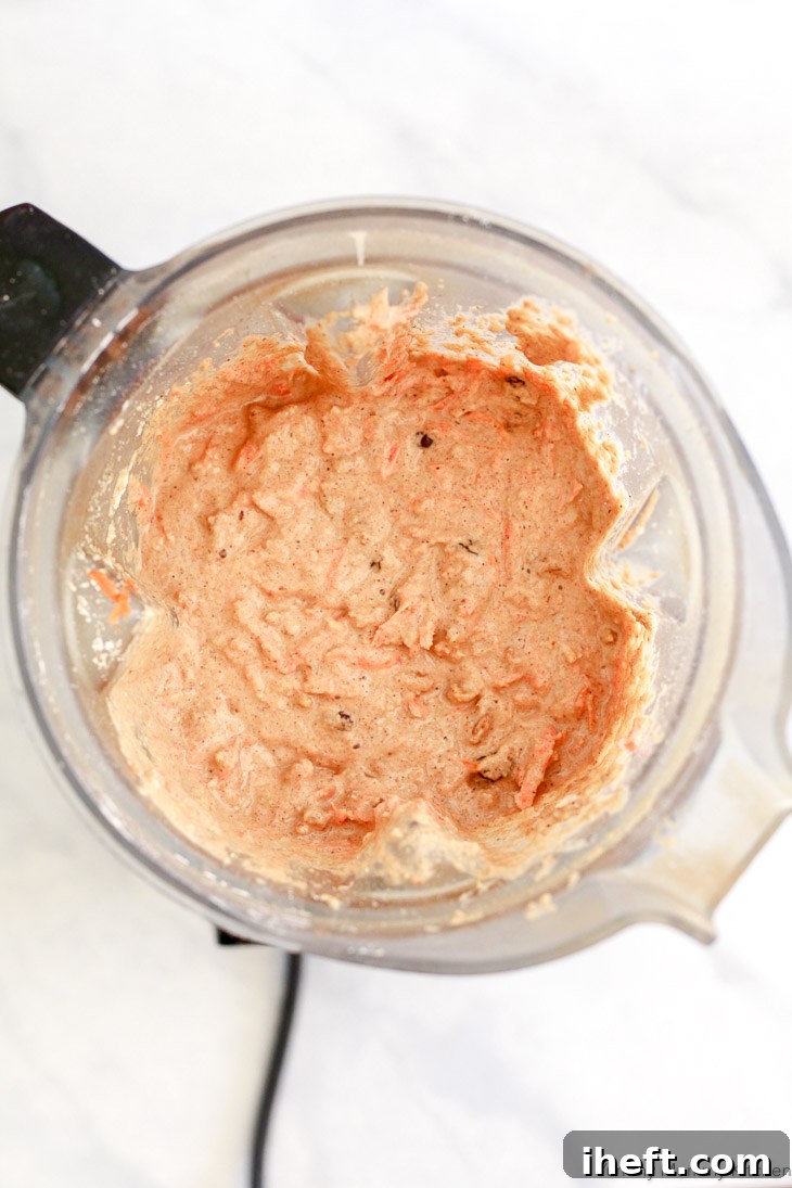 Healthy carrot muffin batter being mixed in a high-speed Vitamix blender, demonstrating the ease of preparation for these wholesome treats.