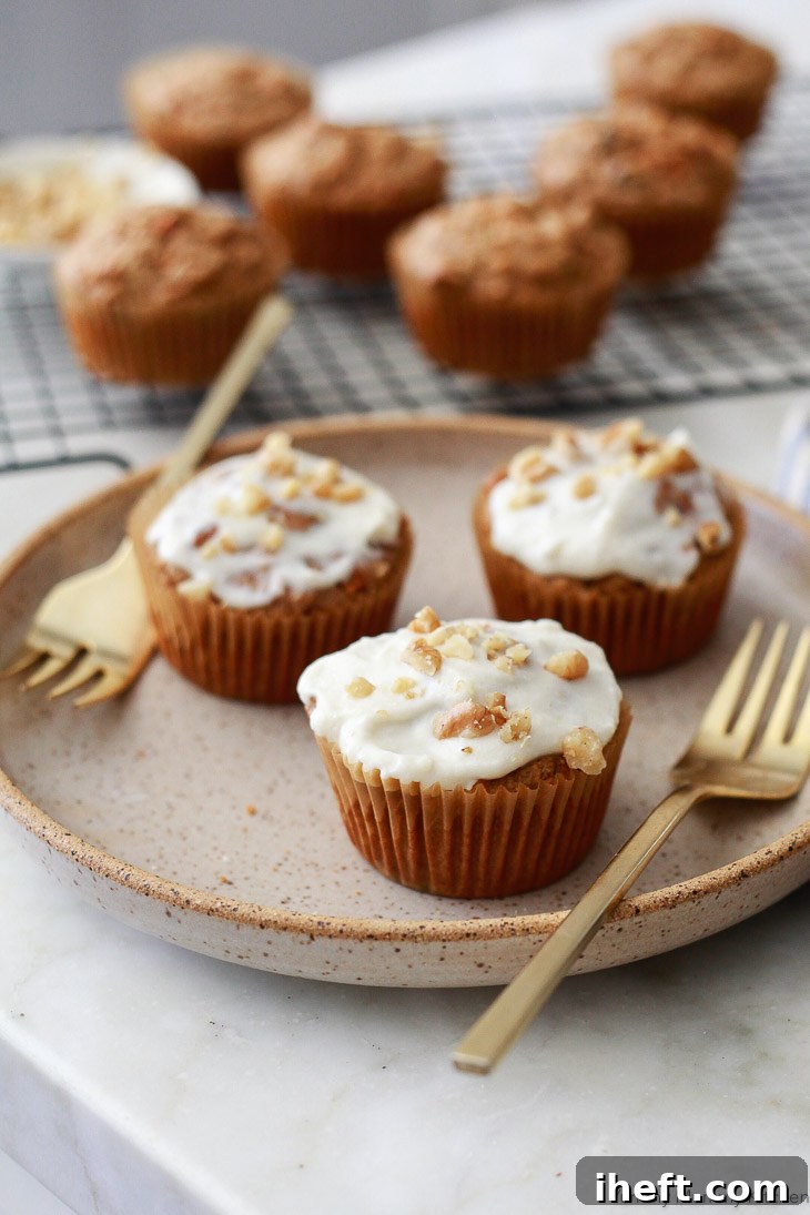 Vegan carrot muffins made with oat flour, topped with a luscious dairy-free cream cheese frosting and a sprinkle of walnuts, emphasizing their dairy-free, oil-free, and gluten-free qualities.