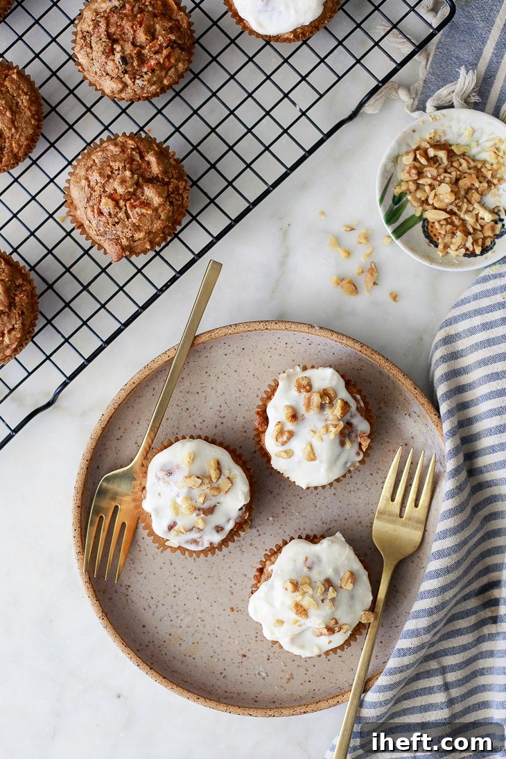 Plate of frosted carrot muffins with forks, garnished with chopped walnuts, showcasing these delicious vegan and gluten-free treats.