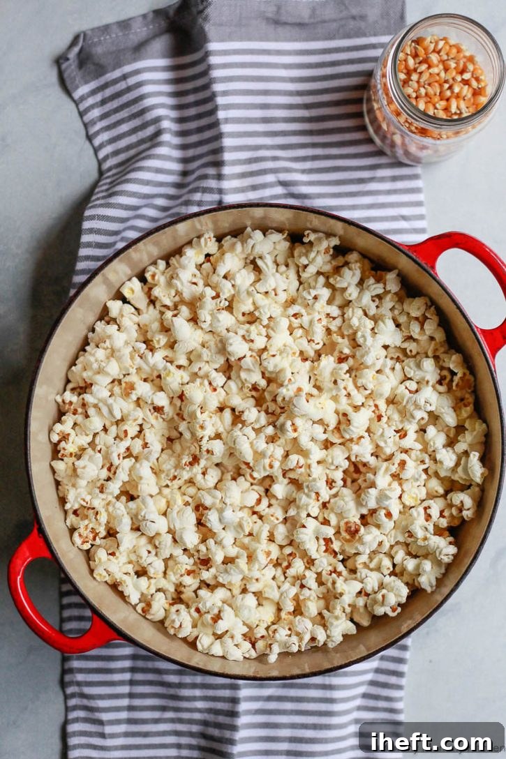 A Dutch oven filled with fresh homemade stovetop popcorn, ready to be seasoned and enjoyed. Learn how to make the best popcorn on the stove with this easy recipe.