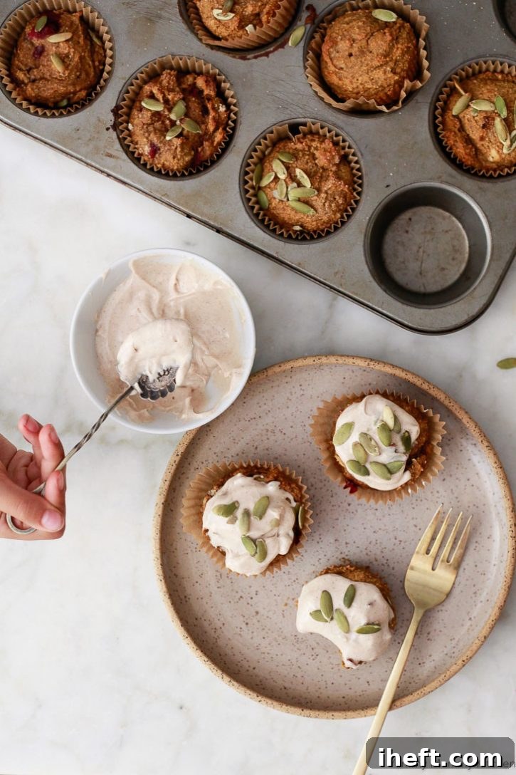 A beautiful photo of making gluten free vegan pumpkin muffins with dairy-free cinnamon cream cheese frosting with pepitas. 