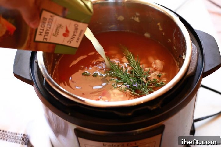 Rich vegetable broth being poured into the Instant Pot, joining the medley of vegetables, beans, and pasta to create a delicious and easy minestrone soup recipe.