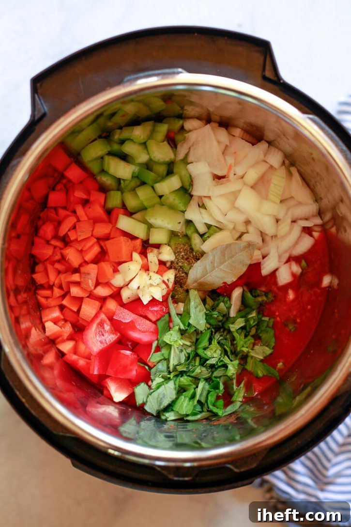 All the fresh ingredients for homemade spaghetti sauce, including chopped vegetables and canned tomatoes, are meticulously prepared and ready to be cooked in an Instant Pot or Crockpot.