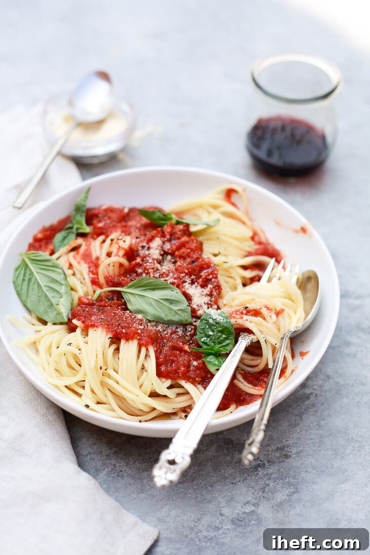 A bowl of spaghetti topped generously with healthy vegan crockpot spaghetti sauce and fresh herbs, ready for serving.