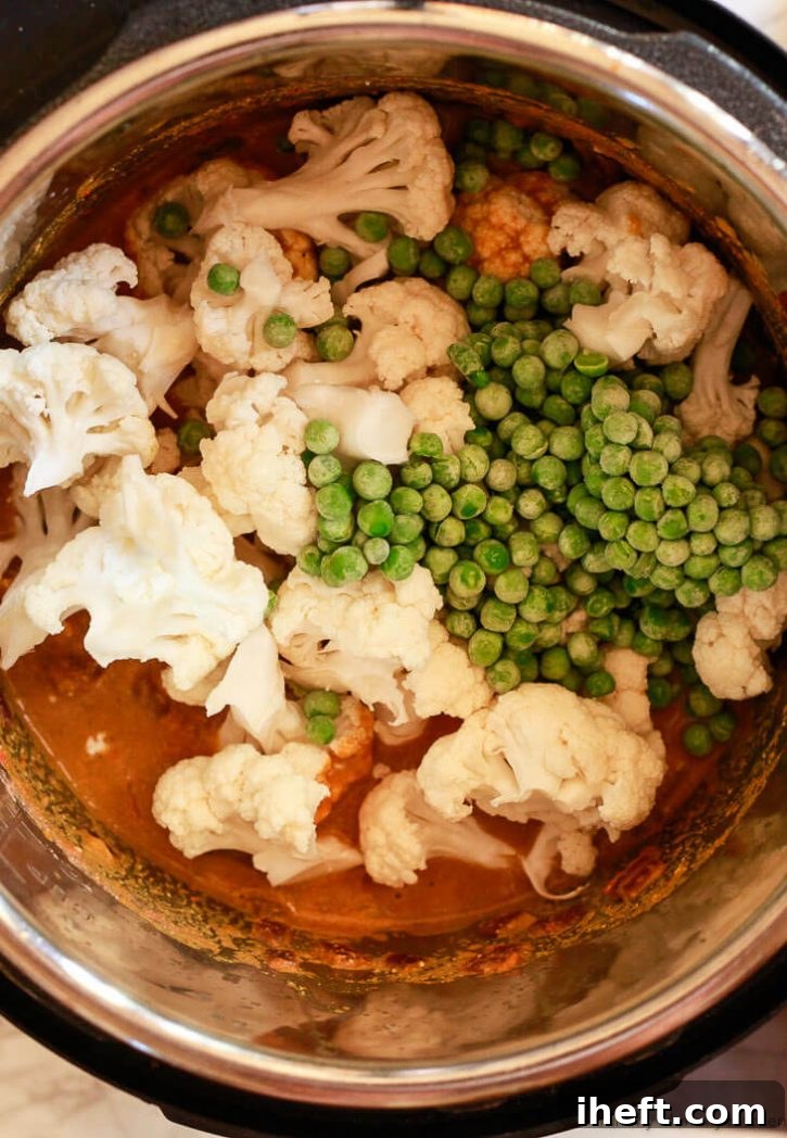 Instant Pot Indian Cauliflower and Pea Coconut Curry Recipe (Gobi Matar Korma) with cauliflower florets and green peas simmering in the rich coconut sauce, ready for pressure cooking.