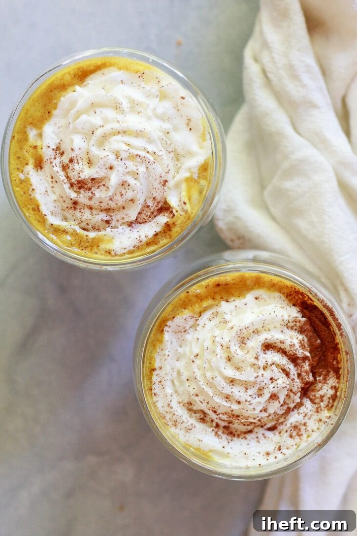 Two golden pumpkin spice lattes topped with whipped cream and pumpkin pie spice. This healthy pumpkin spice latte recipe is vegan and made with turmeric golden milk. 