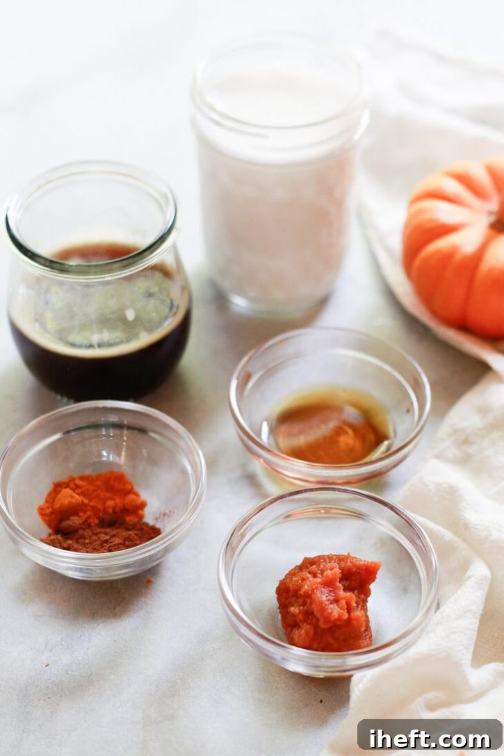 The ingredients for homemade pumpkin spice lattes in bowls: almondmilk, espresso, pumpkin, maple syrup, turmeric, and pumpkin pie spice. 