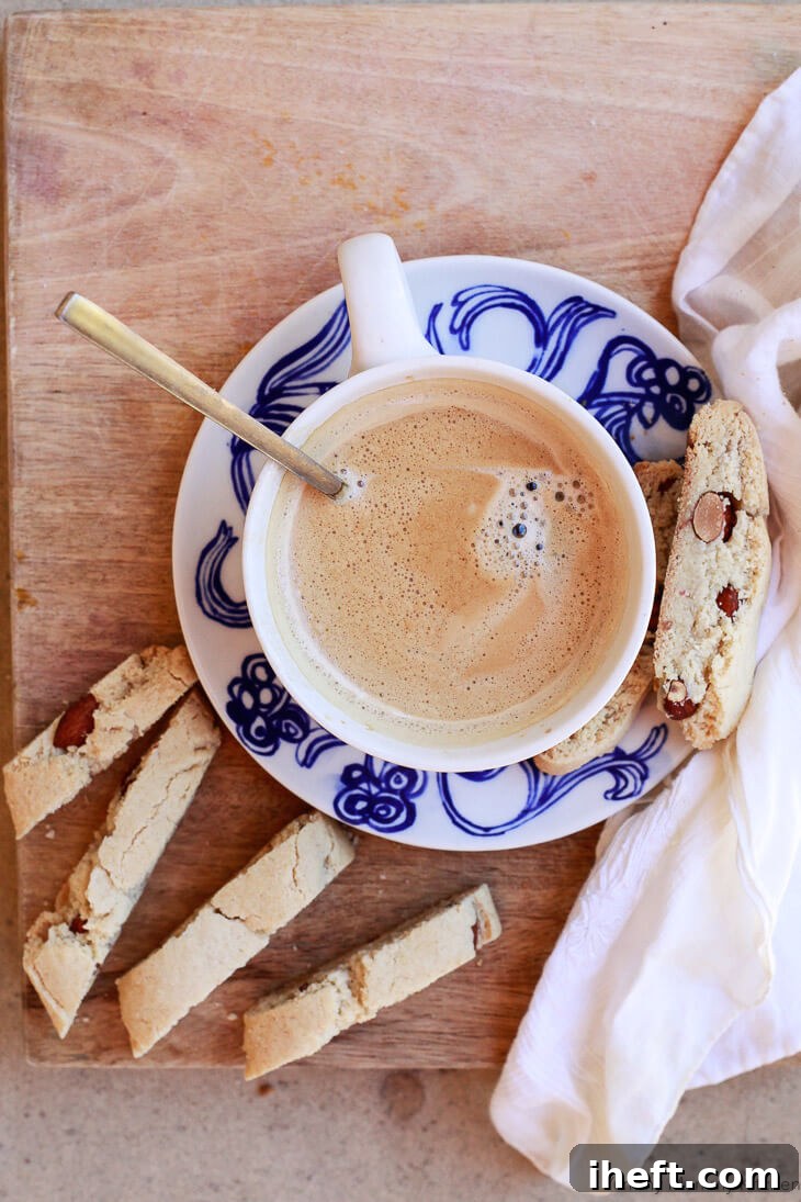 A cup of coffee accompanied by golden-brown almond flour cantucci or biscotti, emphasizing their perfect texture for dunking.