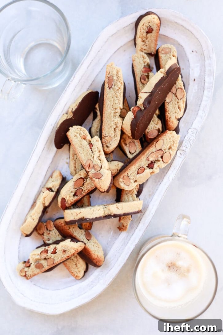 A beautiful platter overflowing with golden-brown gluten-free almond biscotti, each exquisitely dipped in rich, dark chocolate.