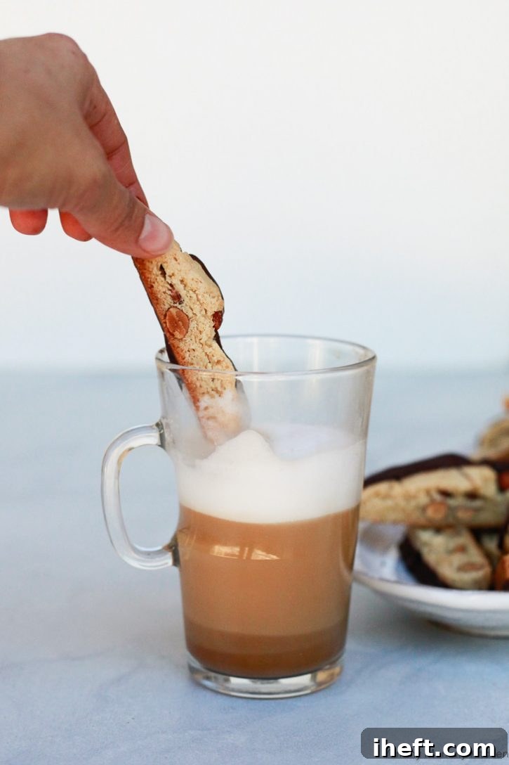 A homemade almond biscotti being dipped into a luscious chocolate hazelnut latte, highlighting the perfect pairing.