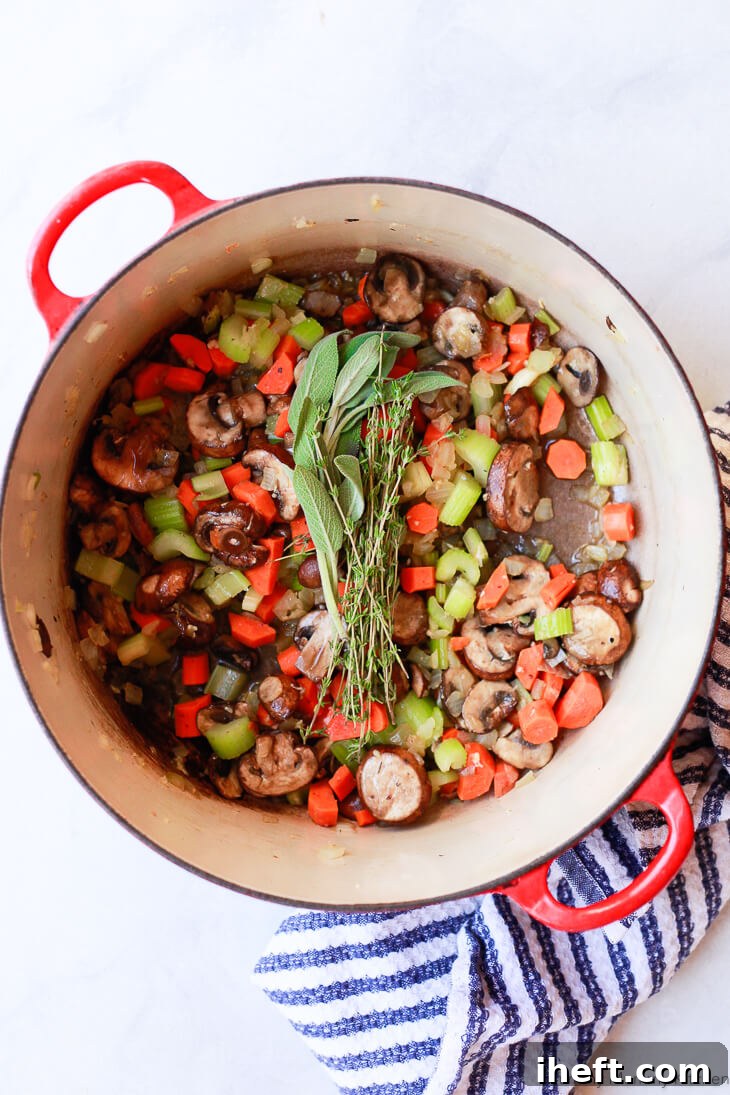 Sauteed carrots, celery, onion, and mushrooms in a pot with fresh sage and thyme. 