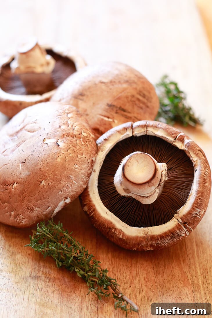 Fresh portobello mushrooms arranged on a cutting board, ready to be prepared as the star ingredient for a delicious and hearty vegetarian mushroom Wellington.