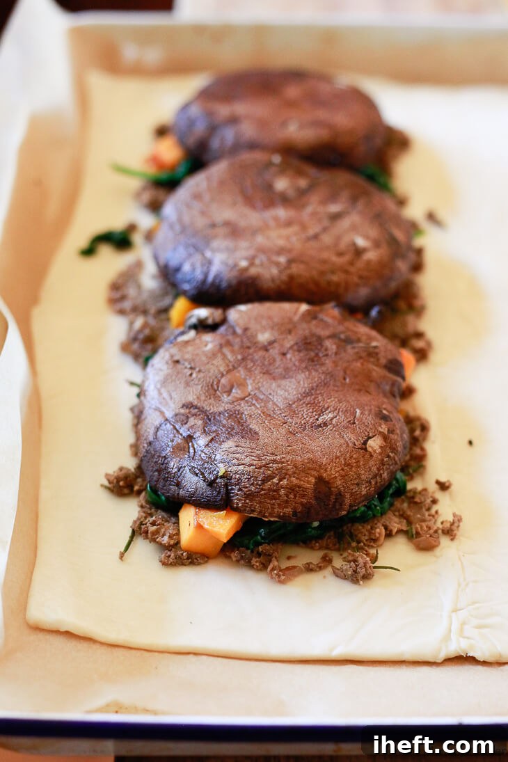 A beautifully assembled Vegetarian Vegan Mushroom Wellington, tightly wrapped in puff pastry and ready for baking, promising a magnificent main course for Thanksgiving or Christmas dinner.