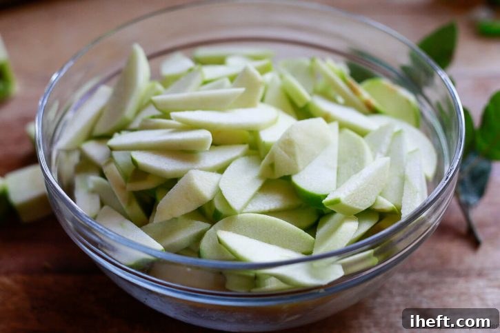 Thinly sliced granny smith apples in a bowl for making vegan apple pie. 