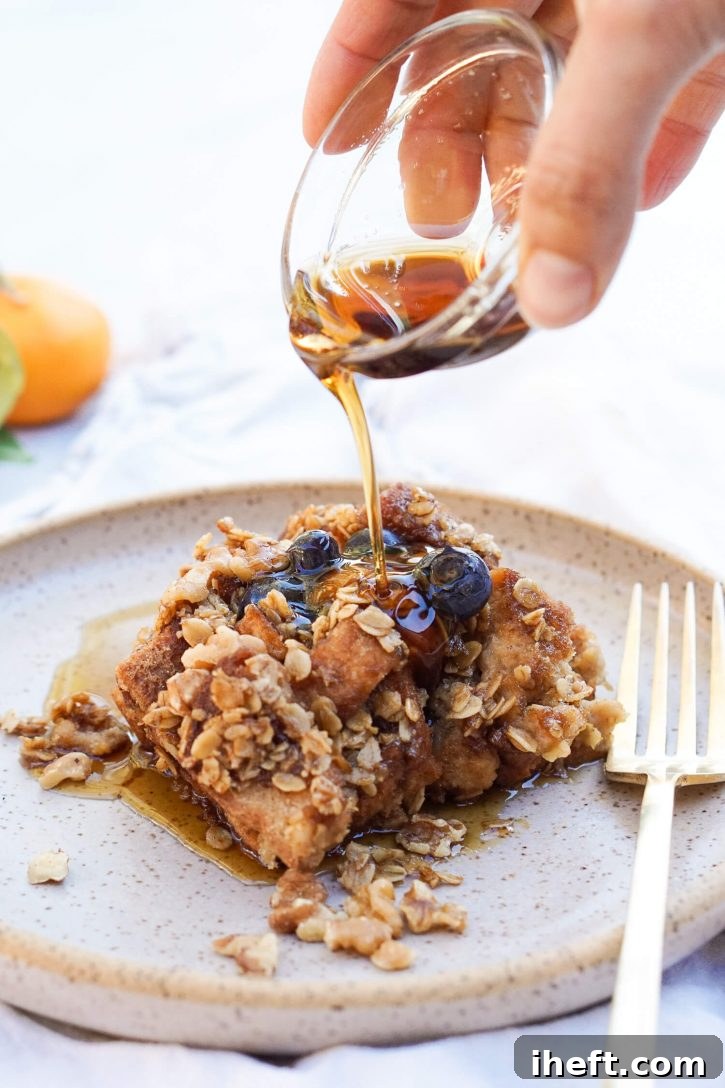 A plate with vegan gluten free french toast casserole with an oat crumble topping. Topped with fresh blueberries, maple syrup is poured over this vegan breakfast treat.