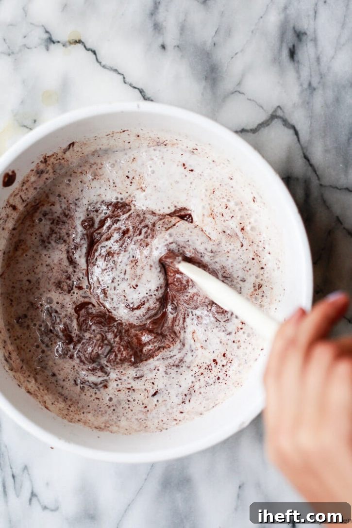 Hot cream and chopped chocolate are stirred together to create a ganache for homemade dark chocolate truffles. 