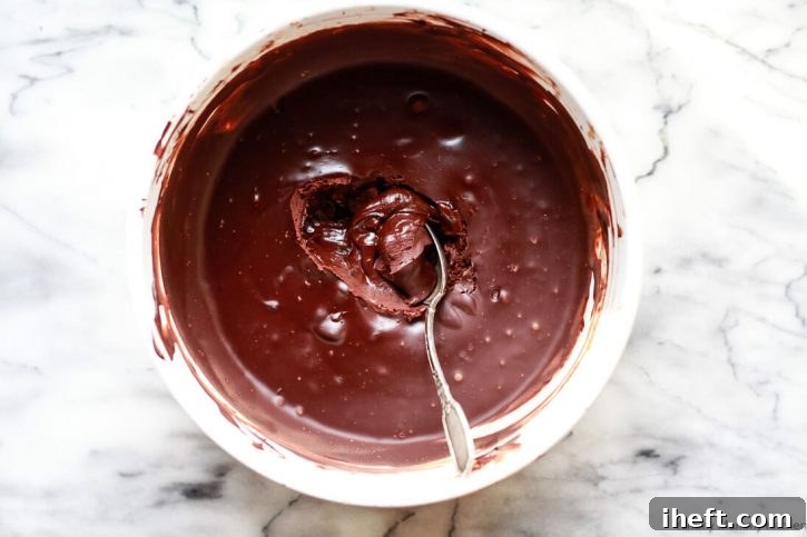 A spoon scoops out hardened chocolate ganache to make dark chocolate truffles. 