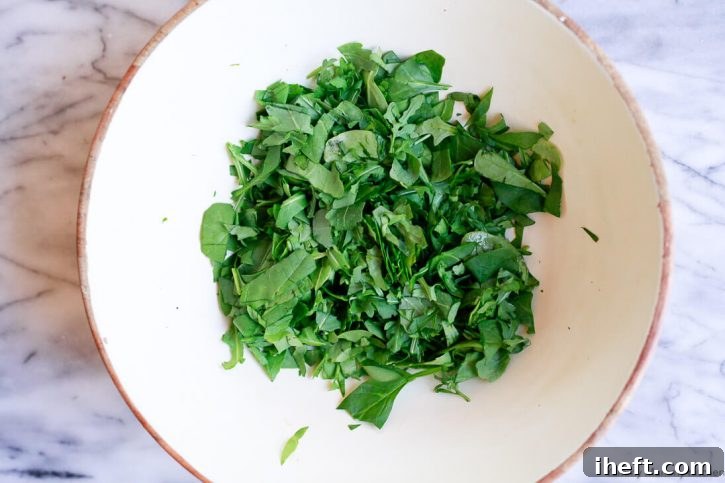 Chopped baby spinach forming the base in a large salad bowl, ready for additional ingredients.