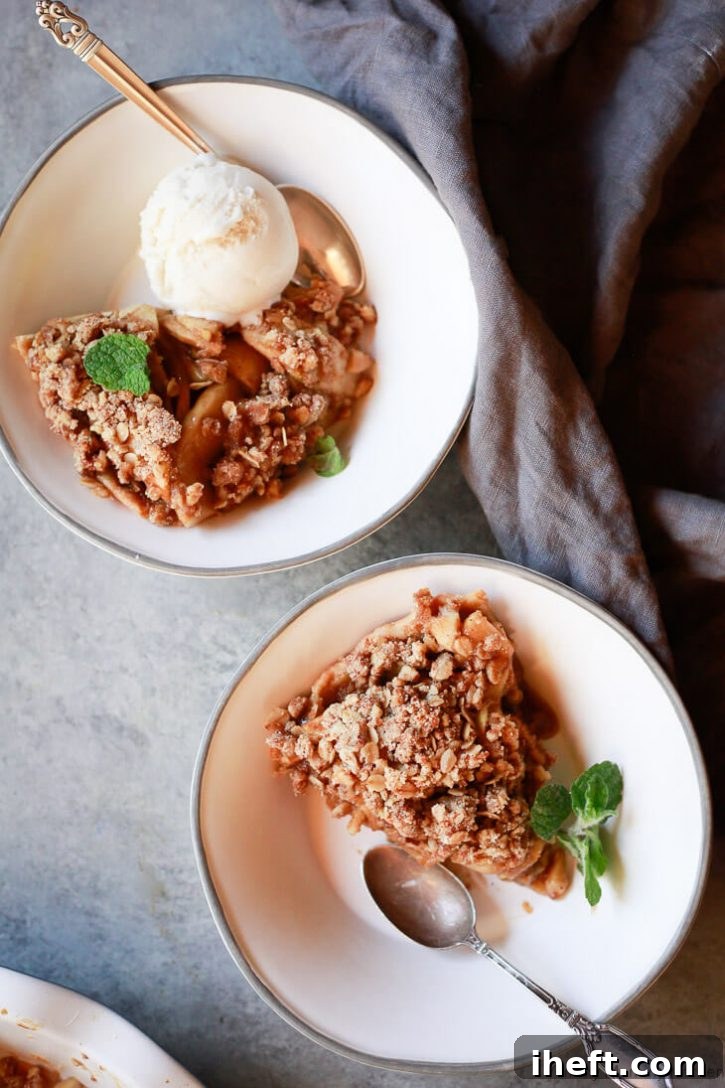 Vegan apple crumble pie slices in bowls with ice cream. 