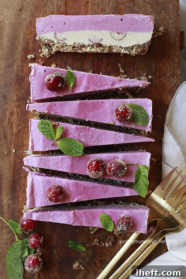 Vegan cranberry cheesecake slices layered with pink and white and a nut date crust. 