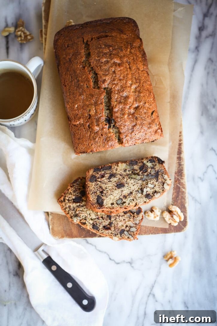 Deliciously moist vegan banana bread, studded with walnuts and chocolate chips, served on a rustic cutting board.