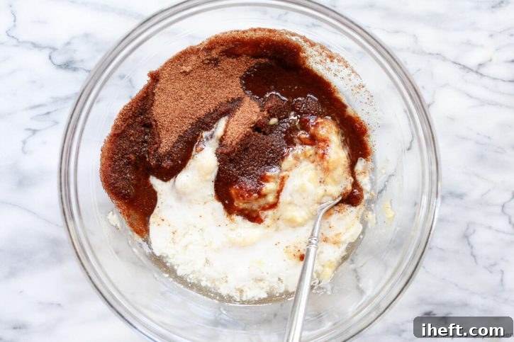 Wet ingredients for vegan banana bread being whisked together in a large mixing bowl, showing a smooth, creamy texture.
