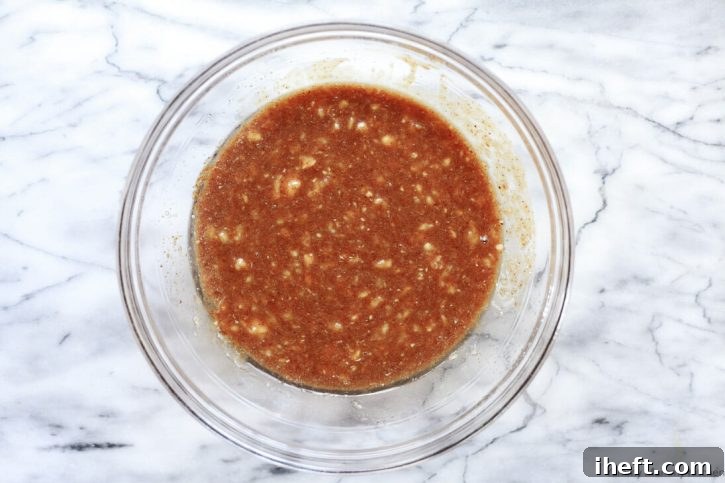 Wet ingredients for vegan banana bread, including mashed bananas, plant milk, sugar, and applesauce, blended smoothly in a bowl.