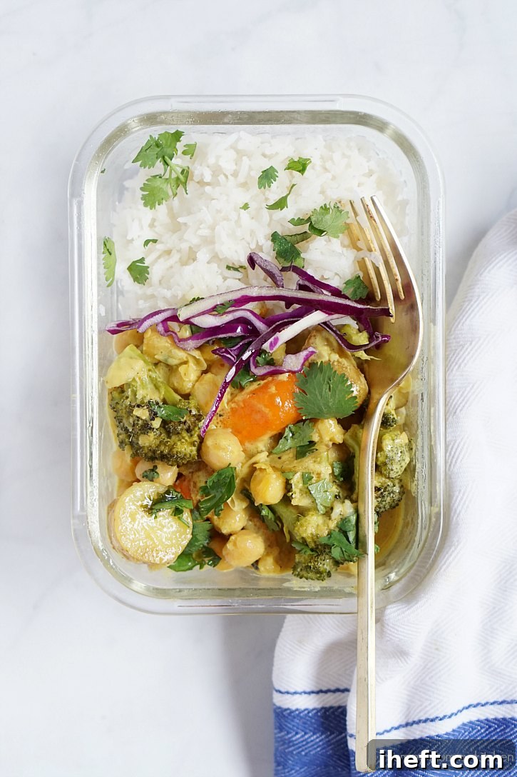 A glass meal prep container with rice and a yellow chickpea curry. 