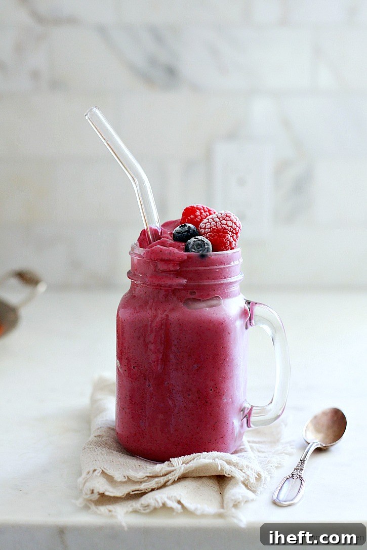 A vibrant purple berry cauliflower smoothie in a glass, garnished with fresh berries. A delicious and beautiful way to eat more hidden veggies and boost nutrition!