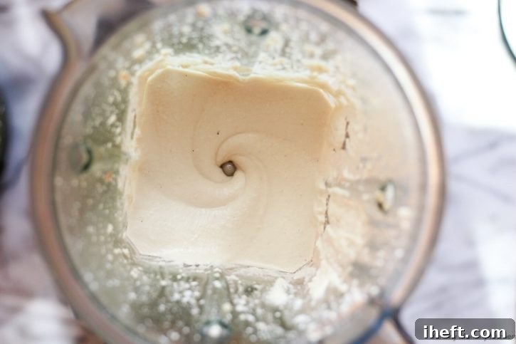 Smooth and creamy white vegan cream cheese sits at the bottom of a Vitamix blender. 