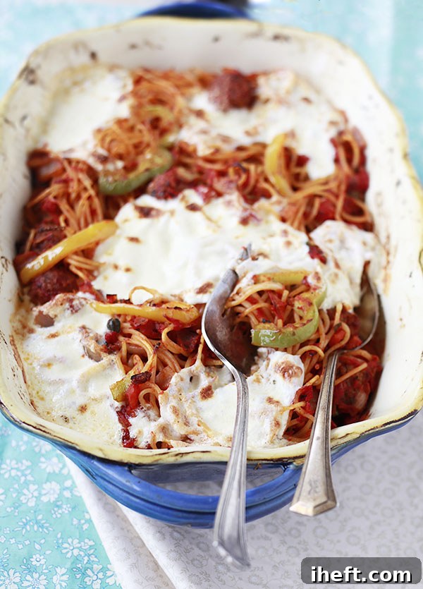 Close-up of a baked spaghetti dish, showing melted cheese and rich tomato sauce bubbling.