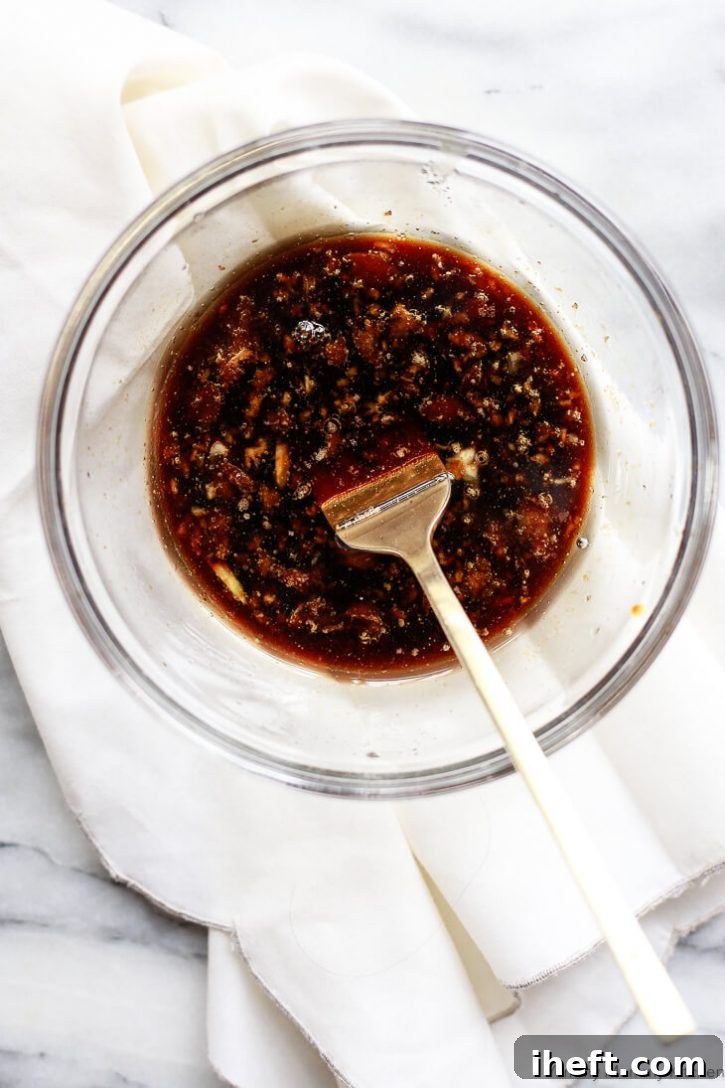 A small glass bowl brimming with a fragrant mixture of soy sauce, fresh ginger, minced garlic, and rice vinegar, poised to become a delectable glaze.